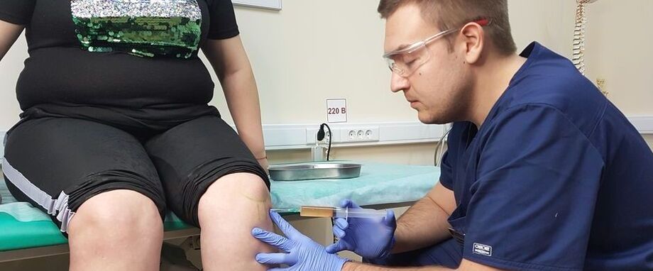 Un medic ortoped face o injecție intra-articulară în articulația genunchiului pentru osteoartrita